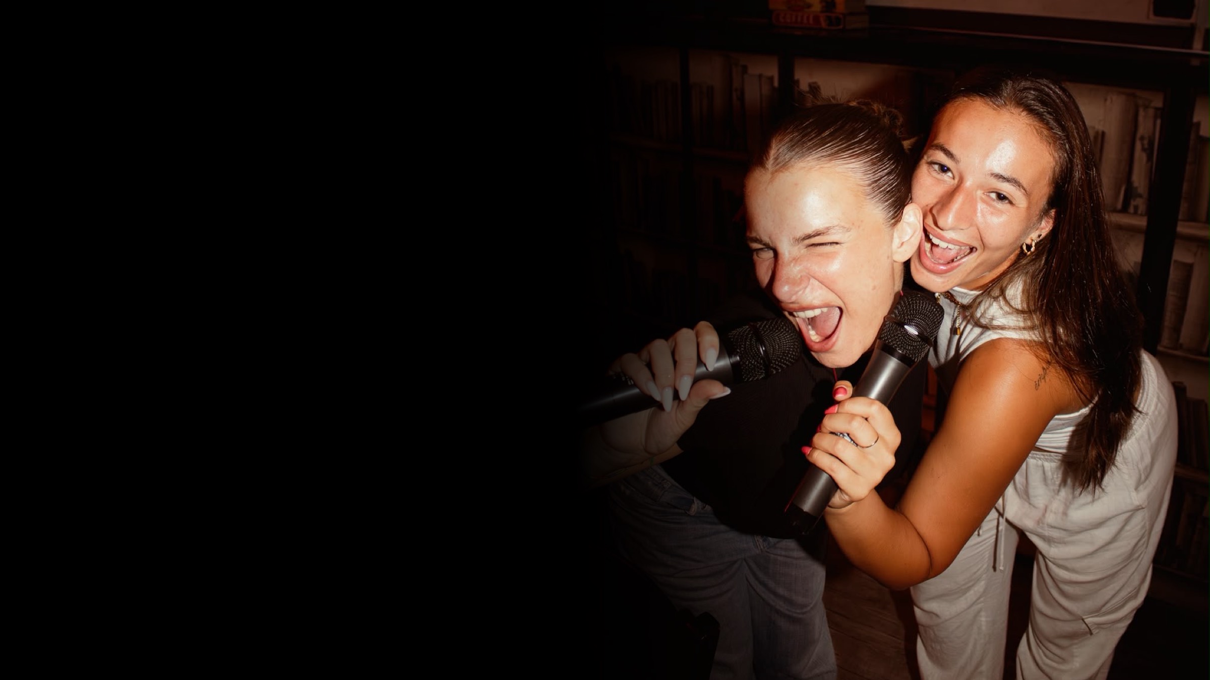 Due amiche cantano urlando al microfono durante una festa privata