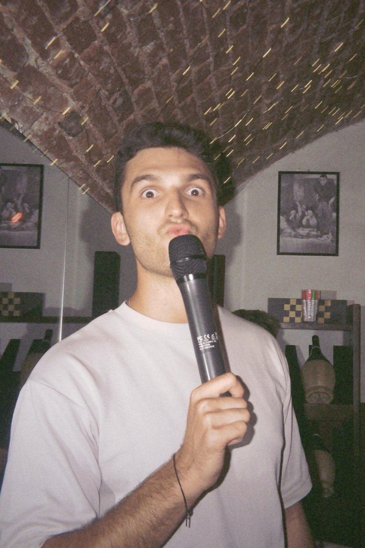 Ragazzo canta al microfono sotto la volta in mattoni della cantina
